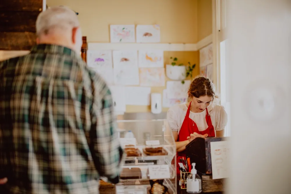 A young business owner serving a customer at her counter