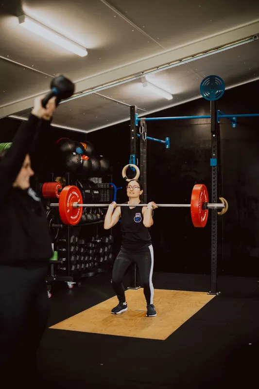 A trainer coaching a client through a barbell lift in a Hunter gym