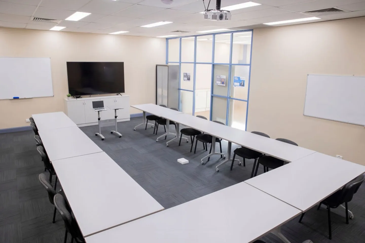 The Hub training room set in a U shape, with wall screens and whiteboards at both ends